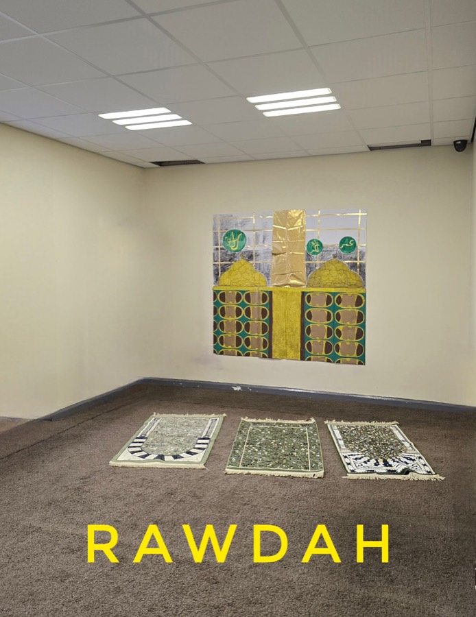 An empty classroom with a gold and green panelled screen laid out on the floor as the Rawdah