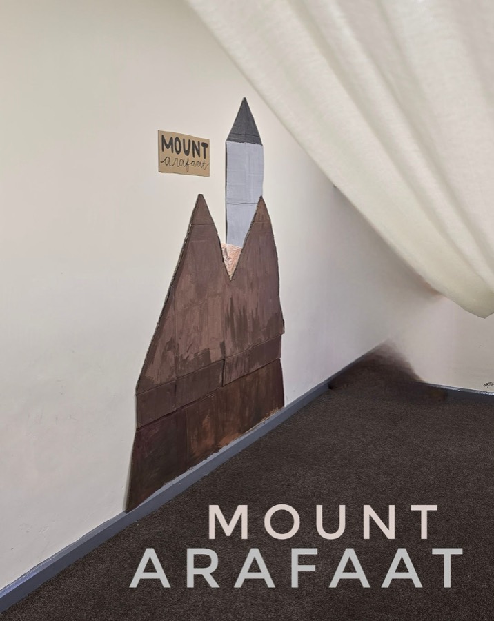 A dark painted mountain built from card, reaching the ceiling, with a white sheet draped beside it