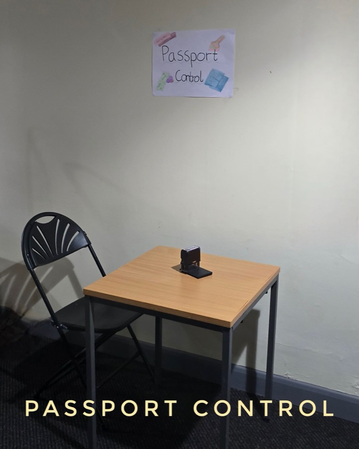 A small table and chair set up in a corridor as a passport control desk