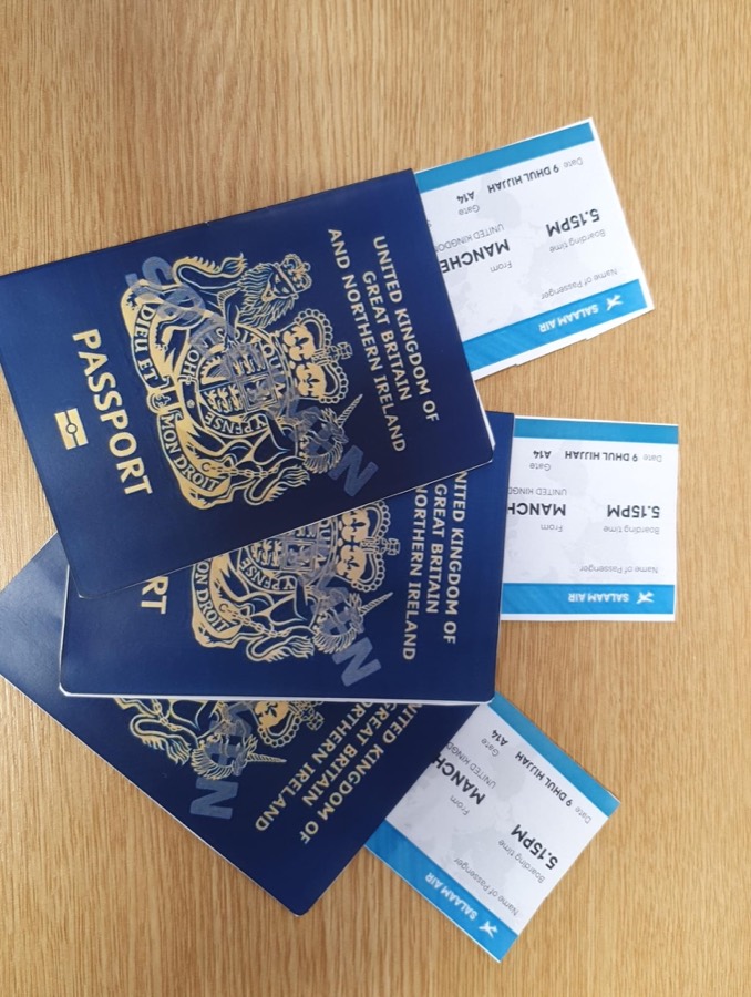 Hand made navy passports and printed boarding passes laid out on a wooden table